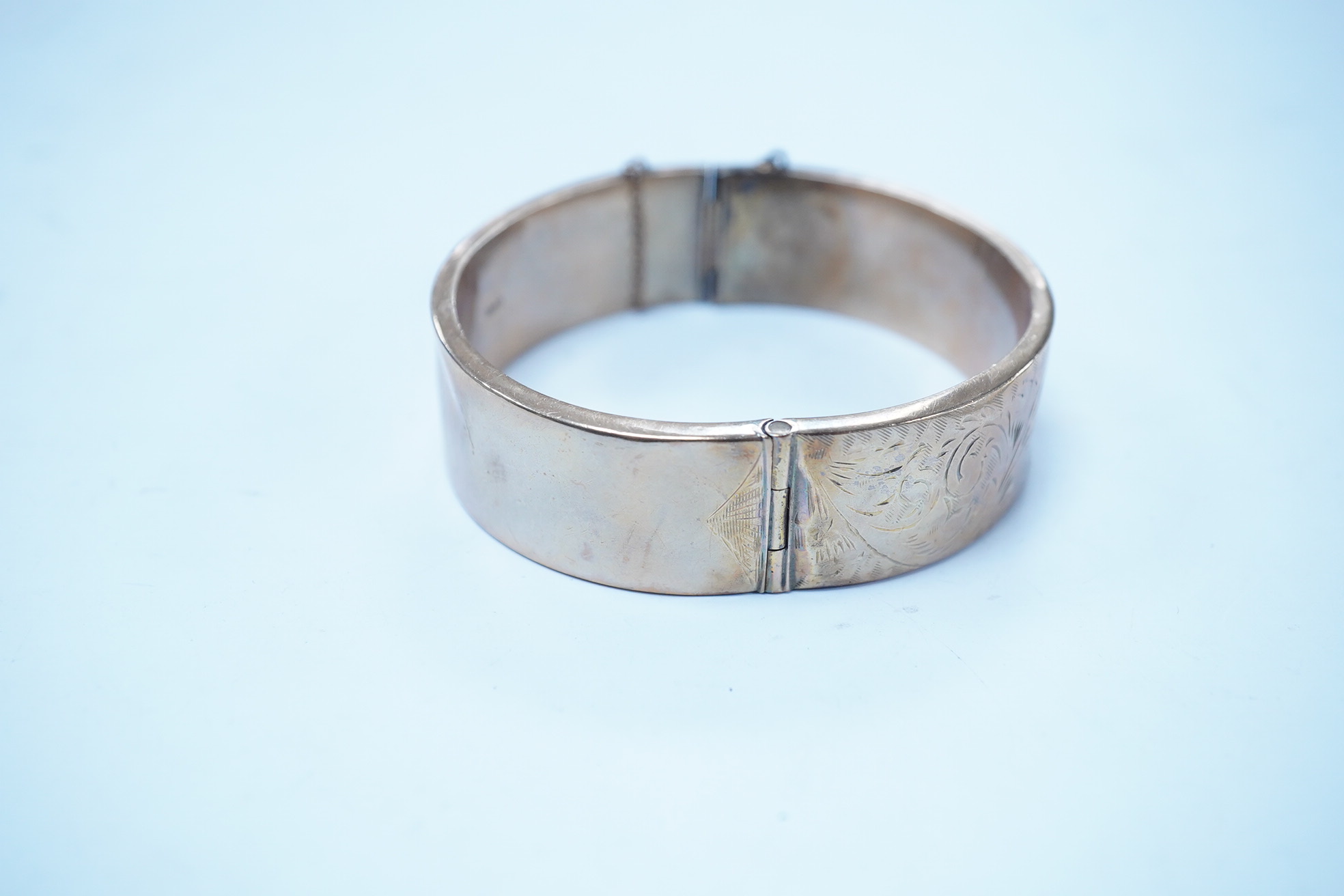 A 1960's engraved 9ct gold hinged bangle, 24.1 grams. Condition - poor